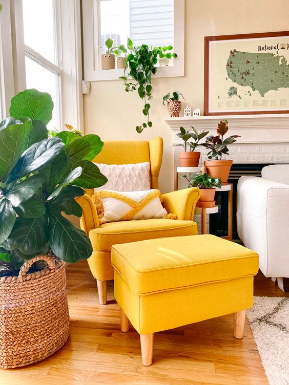 a cozy corner with a yellow Strandmon chair and an ottoman, a fireplace, potted plants and a map wall art is a lovely space