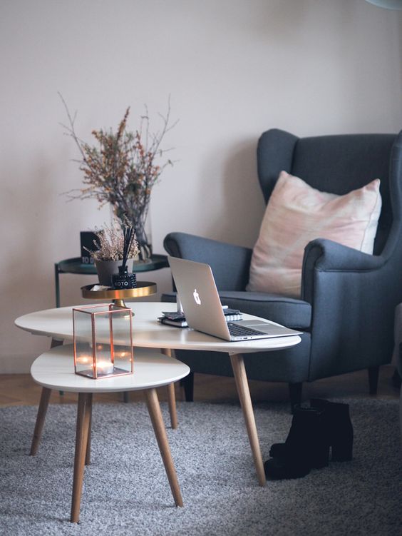 a cozy working nook with a graphite grey Strandmon chair, a couple of coffee tables, a black side table and dried branches in a vase