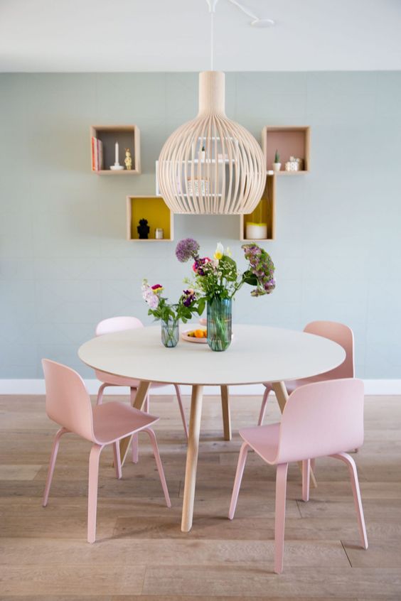  ديكورات غرفة طعام بألوان الباستيل A-delicate-and-subtle-dining-space-with-sage-green-walls-a-round-table-pink-chairs-a-pendant-lamp-and-box-shelves