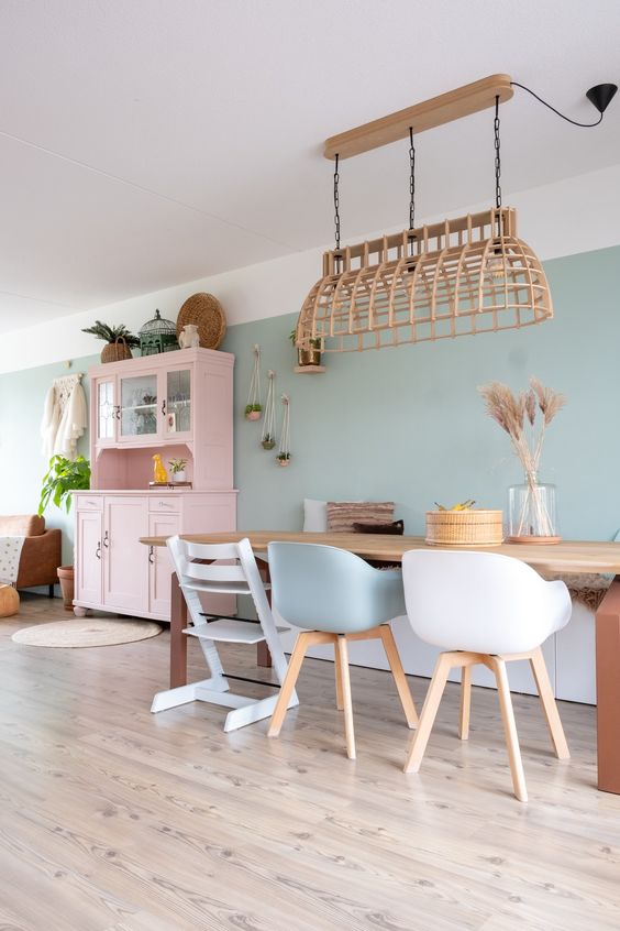  ديكورات غرفة طعام بألوان الباستيل A-delicate-pastel-dining-room-with-sage-green-walls-a-stained-table-white-and-sage-chairs-a-woven-pendant-lamp-and-a-pink-buffet
