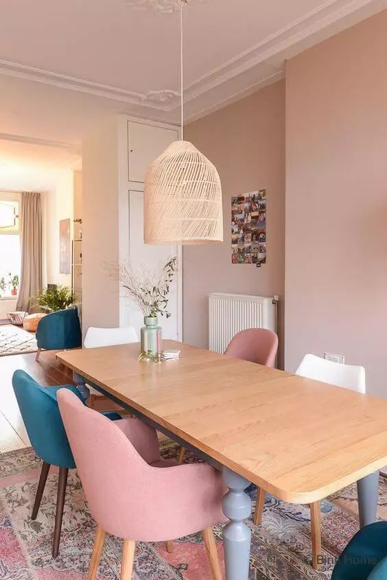  ديكورات غرفة طعام بألوان الباستيل A-dusty-pink-dining-room-with-a-stained-table-dusty-pink-white-and-teal-chairs-a-pink-rug-and-a-woven-pendant-lamp