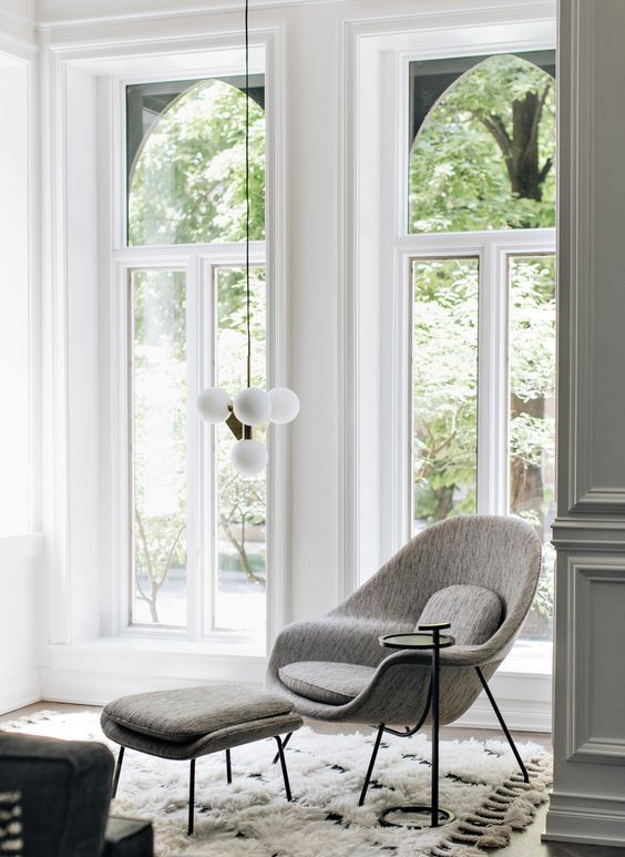a light-filled nook with a fluffy rug, a grey Wo,b chair with an ottoman and a low pendant light to read books