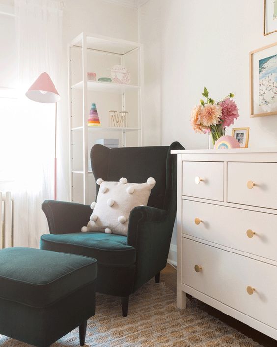 a little nook in the kid's room with a dark green Strandmon chair and a matching ottoman, a dresser and a shelving unit in the corner