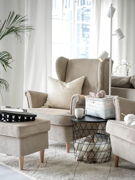 a lovely reading nook with neutral IKEA Strandmon chairs, a matching storage ottoman and a basket storage side table