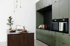 a minimalist olive green kitchen with sleek cabinets, a black backsplash and countertops, a stained kitchen island, gold touches
