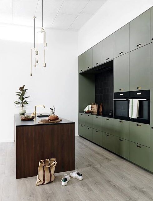 a minimalist olive green kitchen with sleek cabinets, a black backsplash and countertops, a stained kitchen island, gold touches