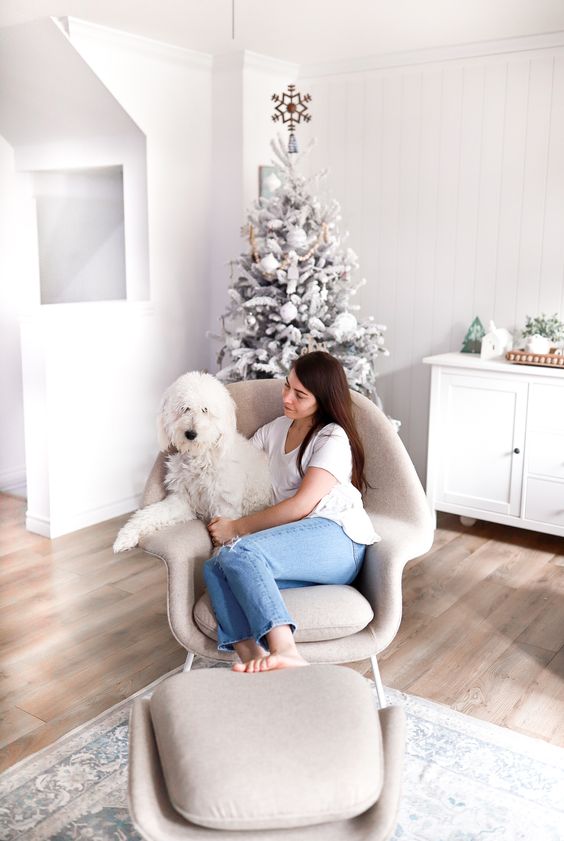 a neutral modern space styled for Christmas, with a white cabinet, a neutral Wumb chair and ottoman, a printed rug