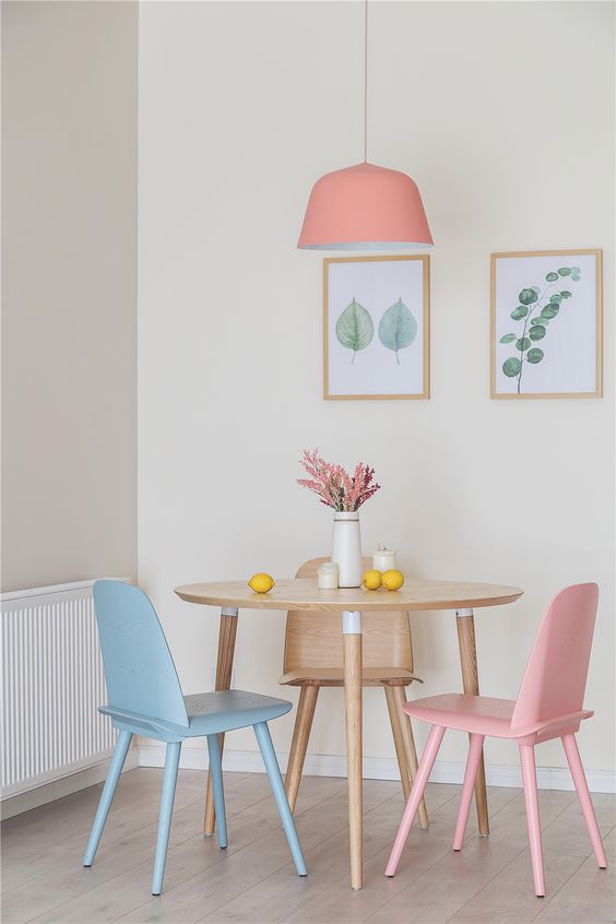  ديكورات غرفة طعام بألوان الباستيل A-pastel-dining-space-with-a-stained-round-table-pastel-chairs-and-a-pink-pendant-lamp-a-mini-botanical-gallery-wall