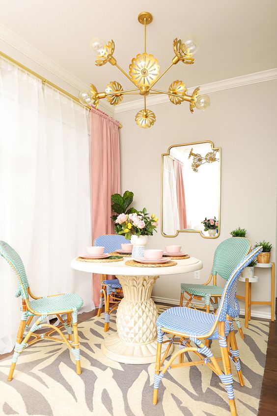  ديكورات غرفة طعام بألوان الباستيل A-refined-dining-room-with-neutral-walls-a-round-table-pastel-chairs-a-gold-chandelier-and-a-printed-rug-plus-pink-curtains