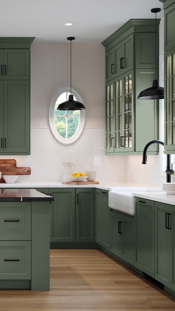 a refined olive green kitchen with glass and shaker cabinets, white and black countertops, a white scale tile backsplash and black handles