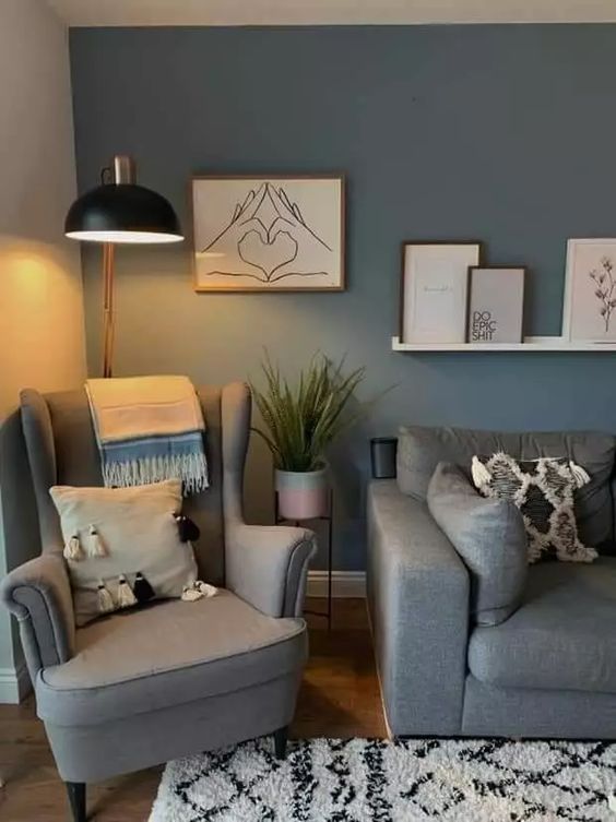 a relaxing Scandinavian living room with a blue accent wlal, a grey sofa and a Strandmon chair, printed textiles and a ledge with a gallery wall