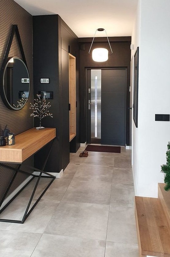 a-stylish-modern-entryway-with-black-walls-and-a-door-a-built-in-storage-unit-a-stained-console-table-and-a-round-mirror.jpg