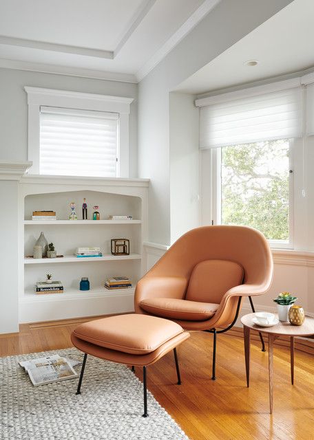 a stylish nook with a built-in shelving unit, an amber leather chair and ottoman, a side table and a rug us cozy and cool