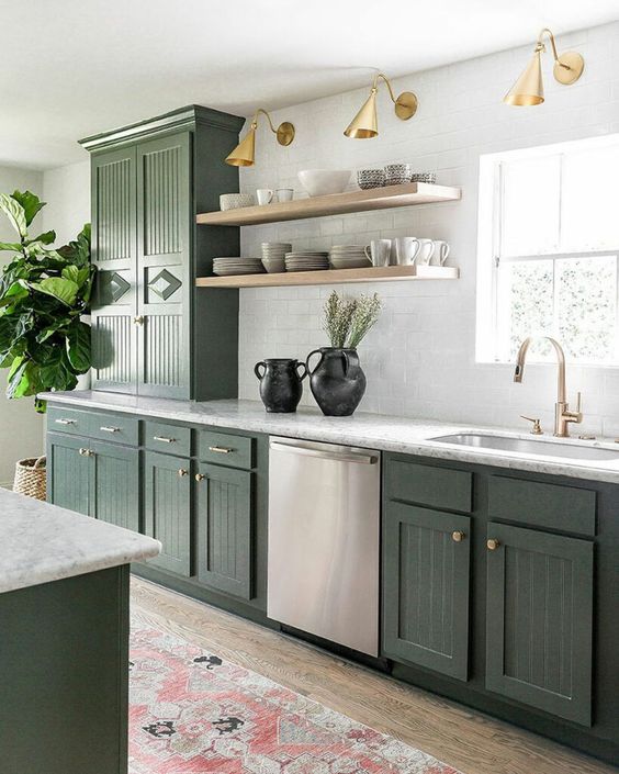 مطابخ باللون الاخضر الزيتي A-stylish-olive-green-farmhouse-kitchen-with-fluted-cabinets-white-stone-countertops-open-shelves-brass-and-gold-lamps