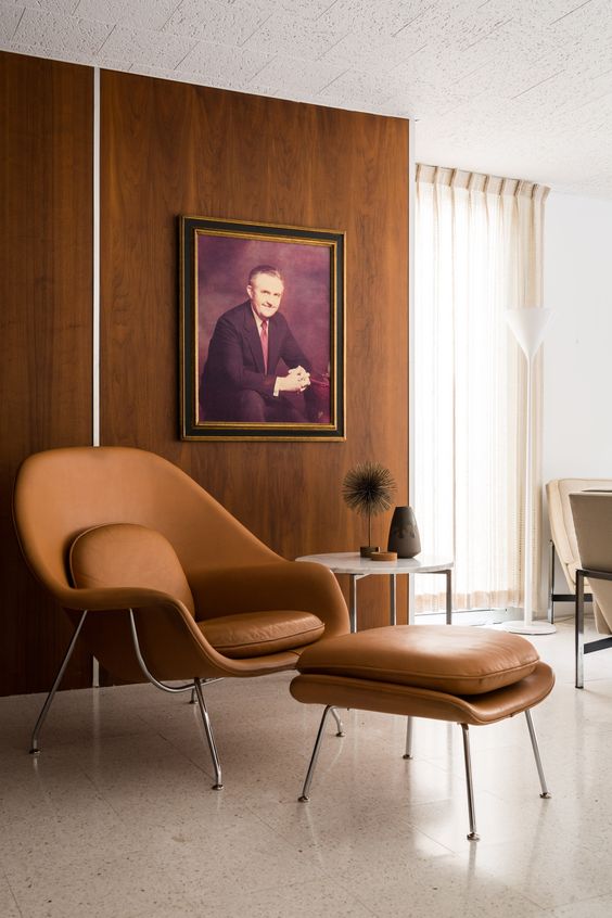 a stylish reading nook with an amber leather Wumb chair and ottoman, a side table and an artwork
