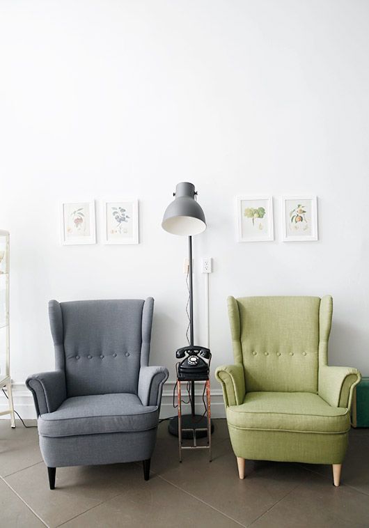 a stylish space wiht a grey and green Strandmon chair, a side table with a phone and a grey lamp, a mini gallery wall