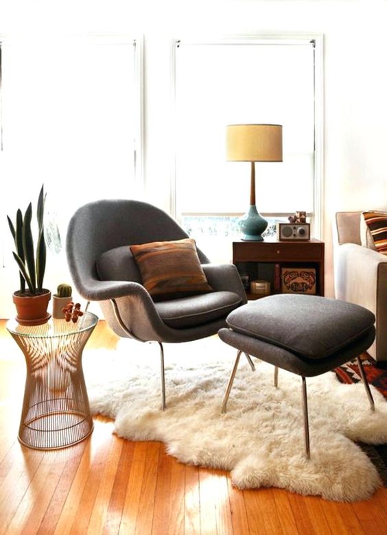 an elegant mid-century modern space with a sofa, a sideboard, a grey Wumb chair and ottoman, a side table with plants