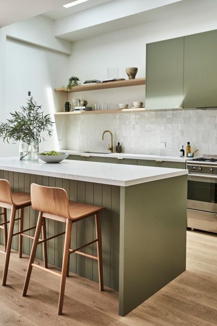 مطابخ باللون الاخضر الزيتي An-elegant-olive-green-farmhouse-kitchen-with-white-Zellige-tiles-on-the-backsplash-open-shelves-wooden-stools