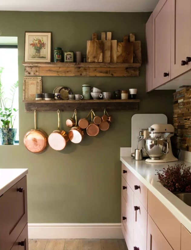 an olive green kitchen with pink shaker cabinets, black knobs, a reclaimed wood backsplash and open shelves
