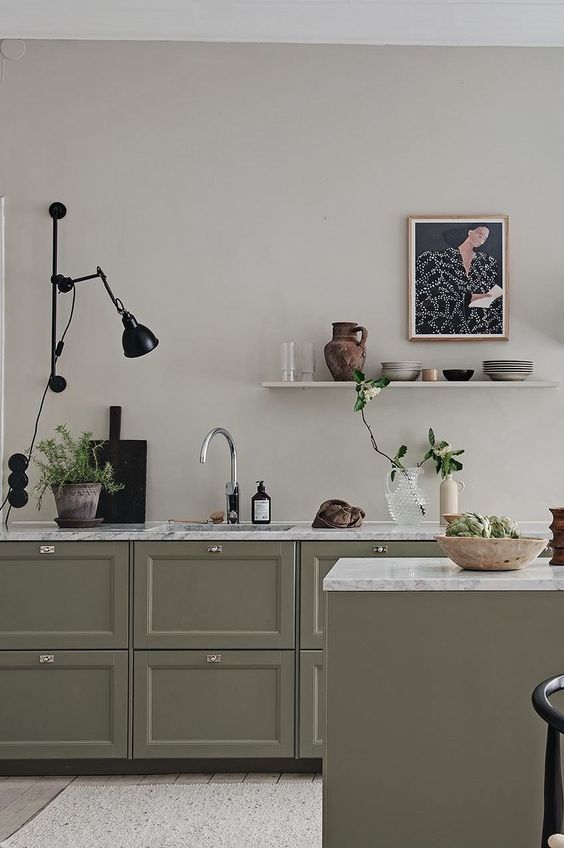 an olive green kitchen with shaker cabinets, white stone countertops, an open shelf, a black sconce and black touches