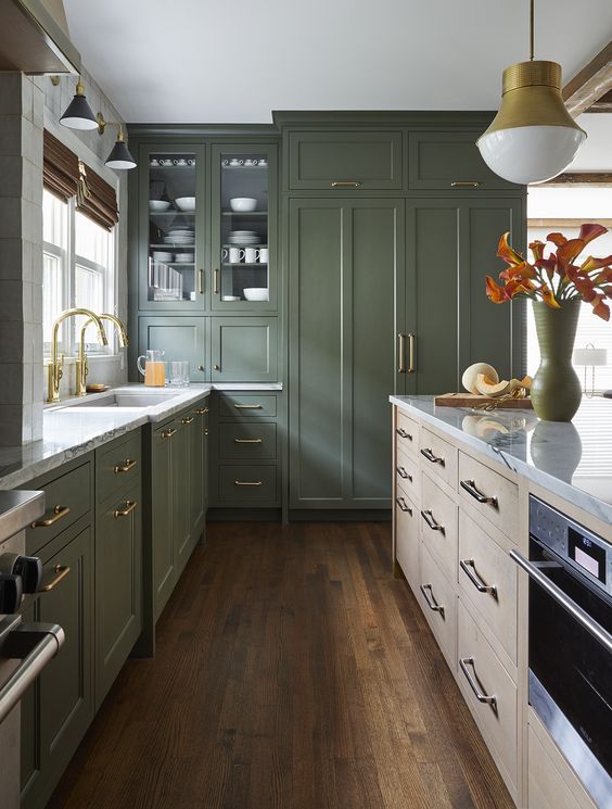 an olive green kitchen with shaker cabinets, a stained kitchen island, white stone countertops and gold fixtures