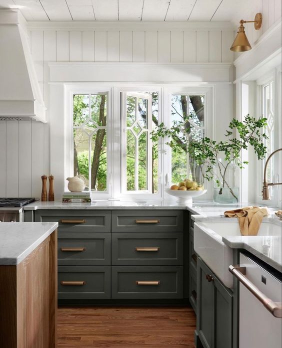 an olive green lower cabinet kitchen with white stone countertops, white beadboard walls and brass and gold fixtures