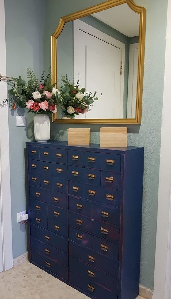 a beautiful navy file cabinet as a console table and dresser for a small entryway, with a mirror with a gold frame and blooms