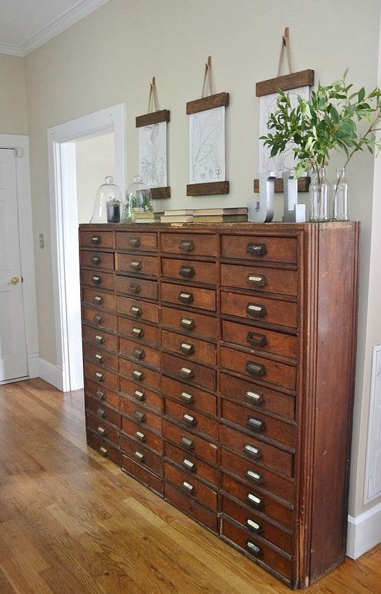 a vintage stained file cabinet is a beautiful and chic solution for an entryway, with vintage books, posters and greenery