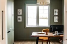 07 a farmhouse olive green home office with a wooden desk and a marigold chair, a pendant lamp and some artwork