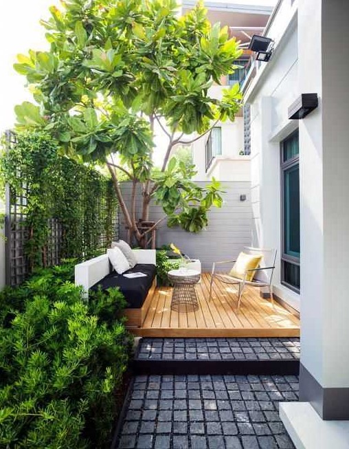 a small contemporary backyard with a wooden deck, a built in daybed and a cool chair, some growing plants and a large living tree a small contemporary backyard with a wooden deck, a built-in daybed and a cool chair, some growing plants and a large living tree