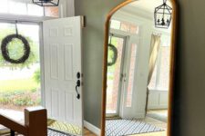 14 a pretty and simple entryway with olive green walls, an oversized mirror in a gilded frame and an elegant lamp