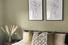 18 a Scandinavian bedroom with olive green walls, a dark green upholstered bed with printed and neutral bedding, a mini gallery wall and a woven pendant lamp