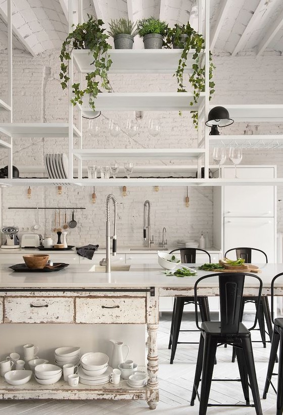 a white kitchen with modern cabinets and a shabby chic kitchen island, suspended shelves, black metal chairs