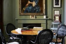 20 a sophisticated dining room with olive green walls, a fireplace, a stained table, black chairs, refined lamps and artwork
