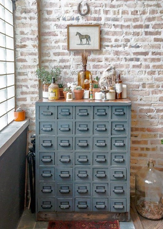 a vintage grey card cabinet with potted plants, dried herbs and candles is a lovely plant stand and storage unit in one