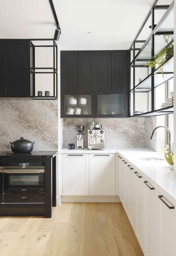 a black and white kitchen with lower white and upper black cabinets, a marble backsplash and suspended shelves that let light in
