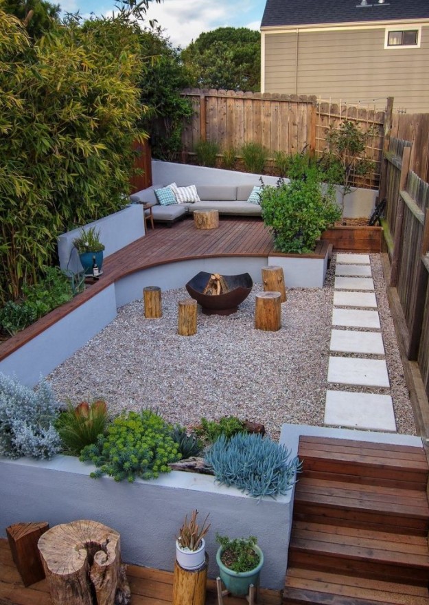 a small and welcoming backyard with a fire pit zone and tree stumps with growing plants and trees, with a raised sitting zone with a sofa a small and welcoming backyard with a fire pit zone and tree stumps with growing plants and trees, with a raised sitting zone with a sofa