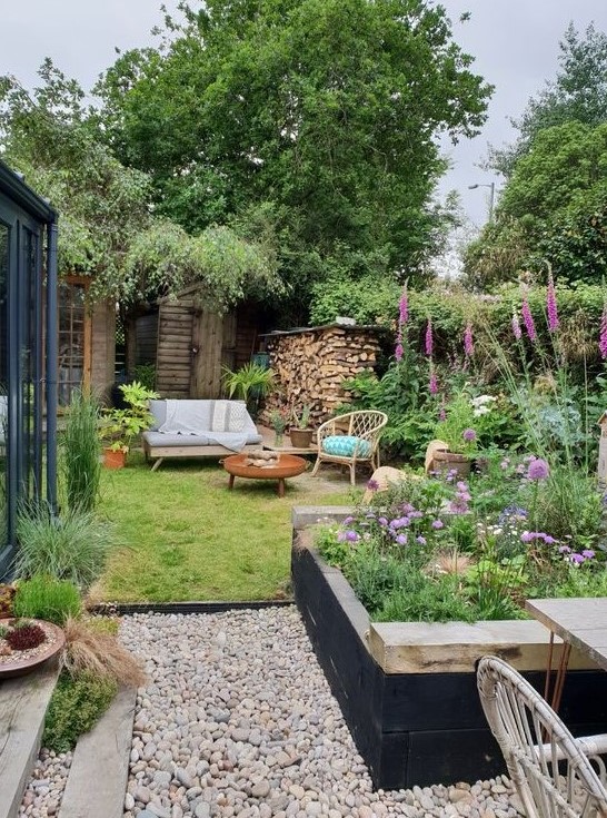 a small and cozy garden with a flower bed, some bright blooms in pots and not only, a lawn and some garden furniture a small and cozy garden with a flower bed, some bright blooms in pots and not only, a lawn and some garden furniture
