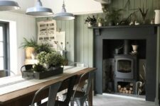 26 an industrial farmhouse dining room with an olive green shiplap wall, a hearth, a wooden table and metal chairs, metal pendant lamps
