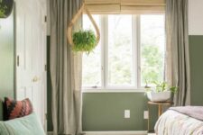 29 an olive green boho bedroom with a bed with printed bedding, a woven bench and pillows, a potted plant and lovely curtains