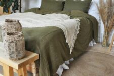 31 a boho bedroom in neutrals, with a bed done with olive green bedding, a wooden bench and woven candleholders, pampas grass, potted plants and burst mirrors