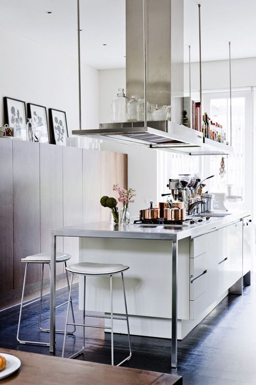 a modern creamy kitchen with suspended shelves over it, a metal countertop and white stools is a cool and chic space