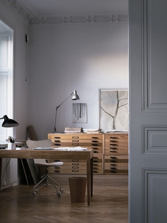 a neutral home office with a stained desk, a white plywood chair, a couple of file cabinets for storage, table lamps is an elegant space