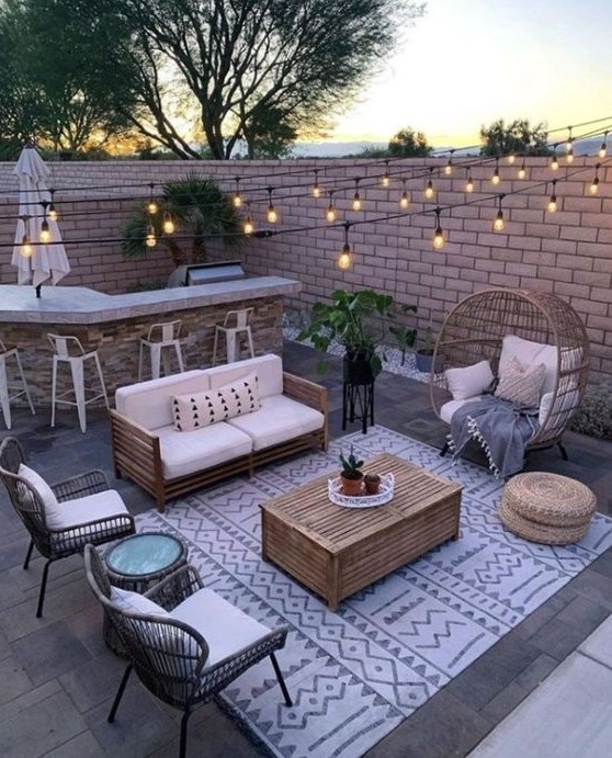 a small paved patio turned into an entertainment zone, with a bar, a sitting zone with rattan furniture and string lights is very cozy a small paved patio turned into an entertainment zone, with a bar, a sitting zone with rattan furniture and string lights is very cozy