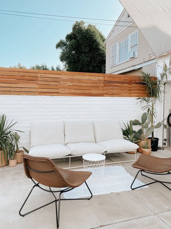 a stylish contemporary backyard with some potted cacti and succulents, with a neutral sofa, wicker chairs and a small side table a stylish contemporary backyard with some potted cacti and succulents, with a neutral sofa, wicker chairs and a small side table