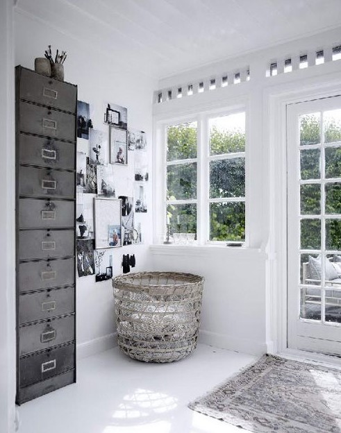 a white Scandinavian space with a black and white gallery wall, a basket, a metal file cabinet as a storage unit and a printed rug