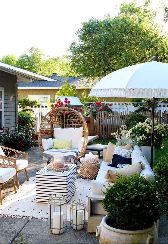 a small paved patio with rattan furniture, candles, potted greenery and bright blooms all around a small paved patio with rattan furniture, candles, potted greenery and bright blooms all around