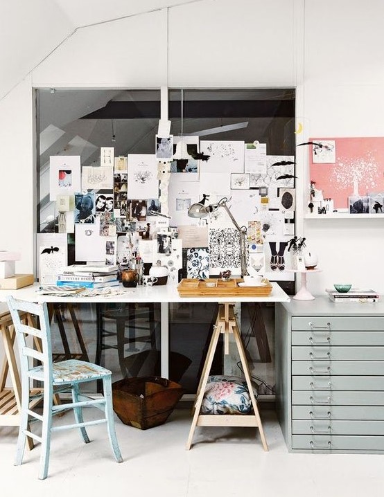 a working space with a trestle desk, a blue chair and a blue file cabinet for storage, a memo board and a table lamp