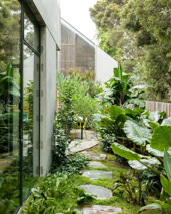 a side tropical mini garden with leaves and greenery, with a small dining space and a rough rock path a side tropical mini garden with leaves and greenery, with a small dining space and a rough rock path