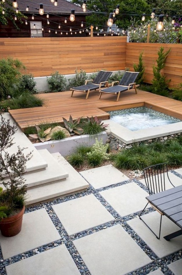 a small modern backyard with a stained fence and deck, with a hot tub, growing plants and loungers, with a dinign table and chairs a small modern backyard with a stained fence and deck, with a hot tub, growing plants and loungers, with a dinign table and chairs